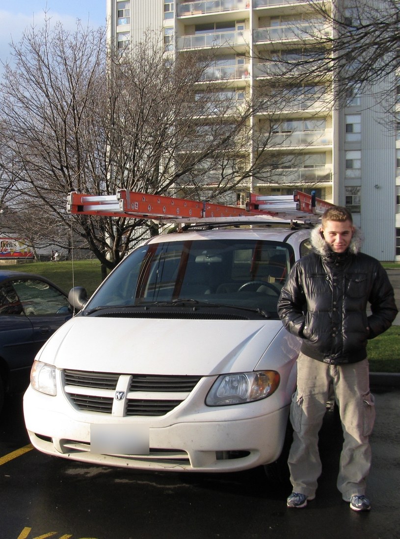 Denis Valasevich in 2009 beside his first work van, two extension ladders strapped to the roof rack, outside a Toronto apartment tower
