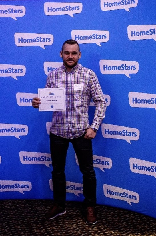 Denis Valasevich holding the HomeStars Best of 2018 certificate in front of a HomeStars branded backdrop