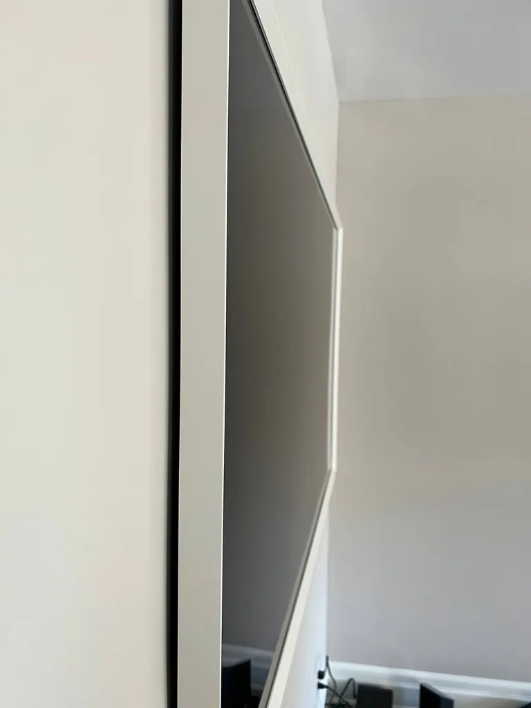 Edge-on view of a flush-mounted TV with a white frame, showing almost no gap between the panel and the wall