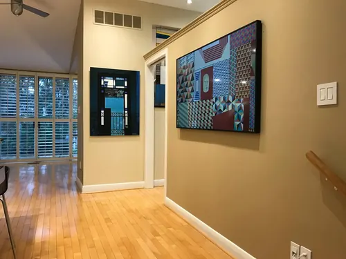 Two Samsung Frame TVs mounted along a hallway, both running artwork so they read as framed pictures