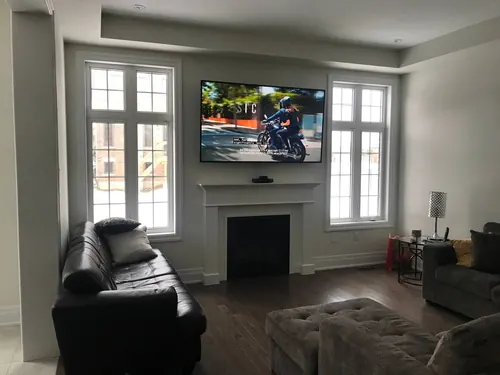 TV mounted above a white painted mantel between two tall windows, with a centre speaker on the shelf