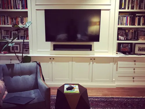 TV recessed into a white built-in bookcase wall, with a soundbar set into its own shelf recess below