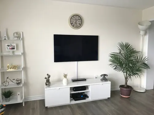 TV mounted on a cream wall with the cable run enclosed in a paintable raceway down to the console