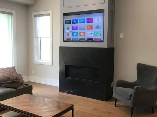 TV set into a bulkhead niche above a dark soapstone fireplace surround with a linear insert