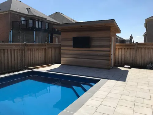 Outdoor TV mounted on the cedar-clad wall of a poolside cabana