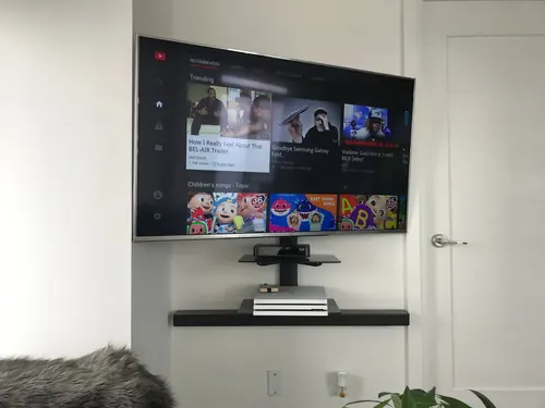 TV, soundbar and a glass AV shelf mounted together on a white wall