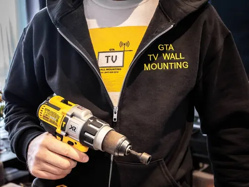 GTA TV Wall Mounting installer in branded workwear holding a cordless impact driver