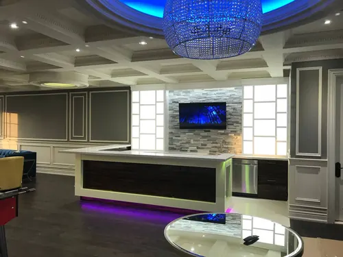 TV mounted on a stone mosaic backsplash in a large entertaining bar under a crystal chandelier