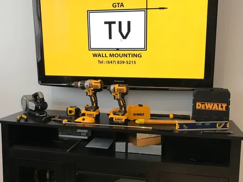 Cordless drills, a level and a stud finder set out in front of a screen showing the company logo