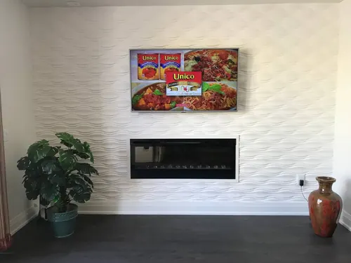 TV mounted on a white three-dimensional wave panel wall above a linear electric fireplace