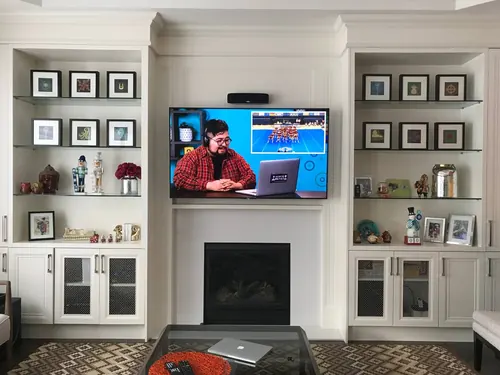 TV recessed into millwork above a traditional gas fireplace, between built-in display shelving
