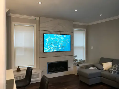 TV mounted on a marble slab panel above a linear fireplace in a family room with a sectional