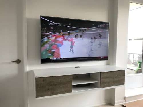 TV mounted on a white wall above a floating console with grey wood drawers