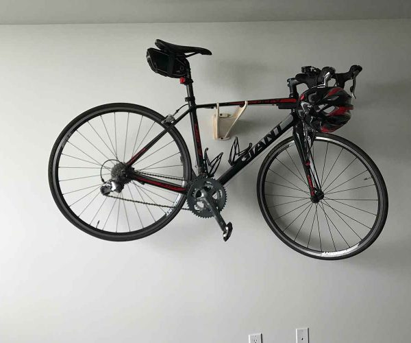 hanging-service-header-bg Road bike mounted horizontally on a wall bracket, helmet hanging off the handlebars