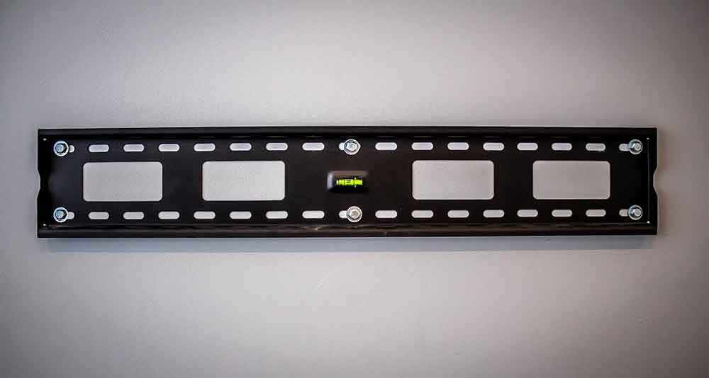 Basic tilting TV wall mount fitted flat to a wall with its long mounting plate visible