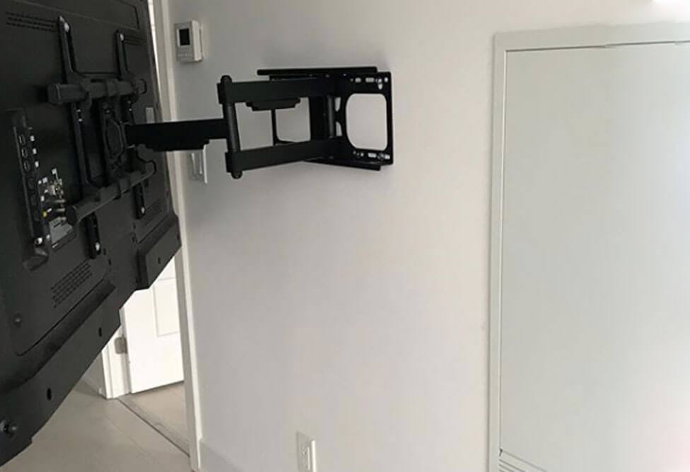 Double arm full motion TV wall mount holding a large flat screen angled away from the wall