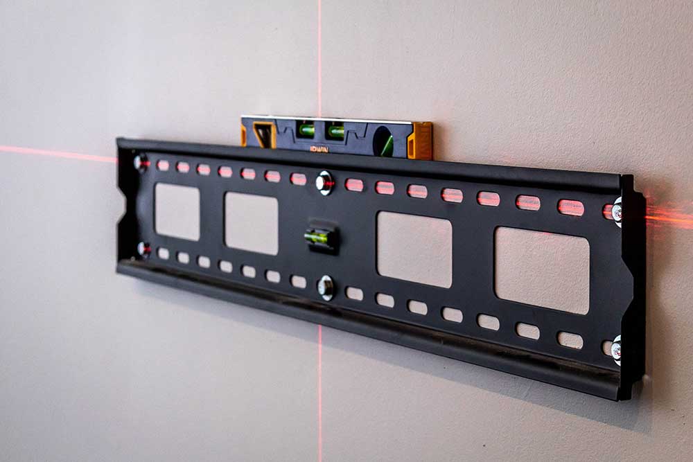 Installer checking a mounted TV bracket with a spirit level before fitting the screen