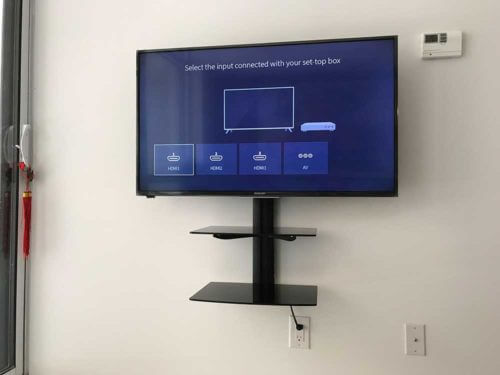 Two floating shelves installed on the wall below a mounted TV