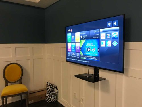 Single floating shelf installed on the wall below a mounted TV