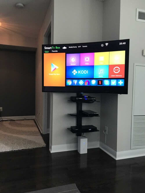 Three floating shelves installed in a stack on the wall beside a mounted TV