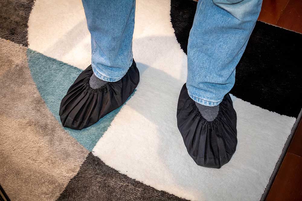 Installer putting on shoe covers at the door before starting a TV mounting job