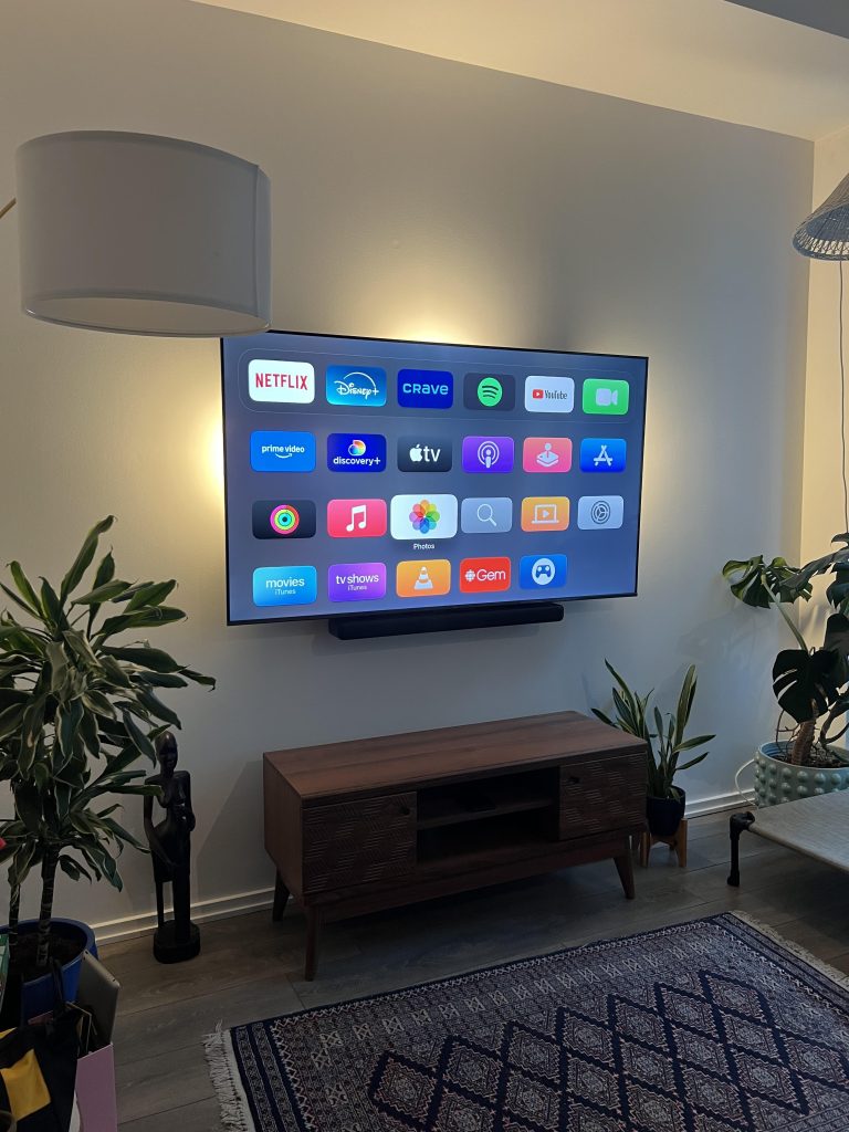 Slim soundbar fixed tight beneath a wall mounted TV in a living room