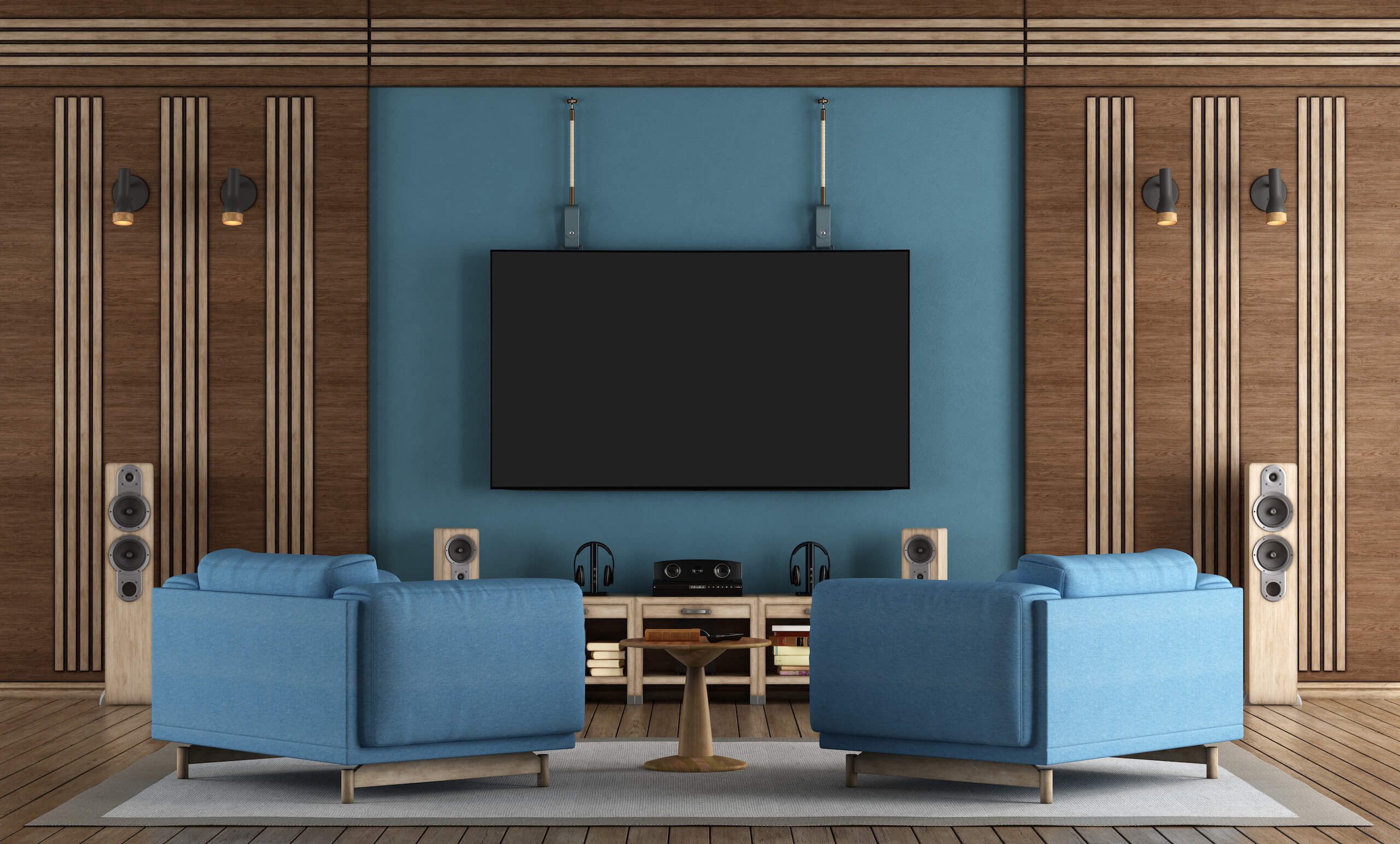 A home theater setup features two blue armchairs facing a large, wall-mounted flat-screen TV. The surrounding decor includes modern wooden paneling, floor-standing speakers, and a small table between the chairs, creating a cozy and stylish entertainment space with impeccable TV wall mounting.